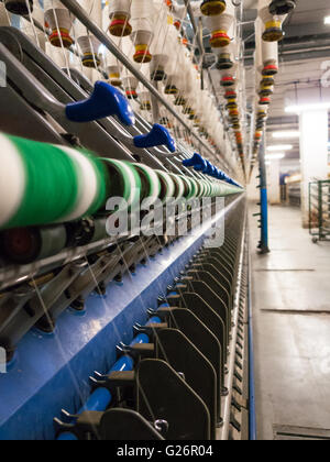 Production heads called spindles on textile spinning frame with individual threads yarns visible in infinite perspective Stock Photo