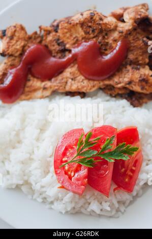 Chicken steak in a dish served with rice and tomato slice. Vertical photo Stock Photo