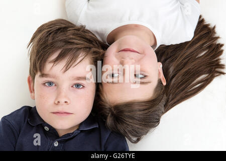 Overhead shot of two children laying on the floor looking up Stock Photo