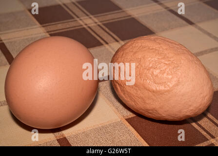 Two eggs on the table one of which is deformed and unhealthy Stock Photo