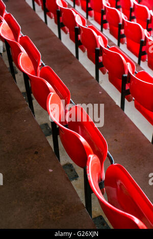 Folded red plastic seats in a sports or football ground. Stock Photo