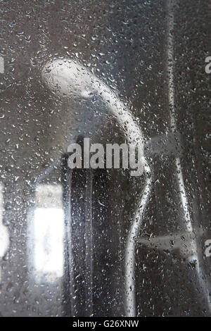 looking through a glass shower door covered in water droplets. Stock Photo