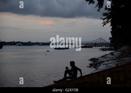 Youth sitting on river bank in monsoon season, Kolkata, West Bengal, India Stock Photo