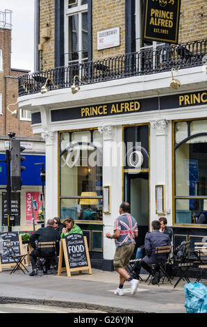 People sit and enjoy a drink outside the Prince Alfred pub in Bayswater, London. Stock Photo