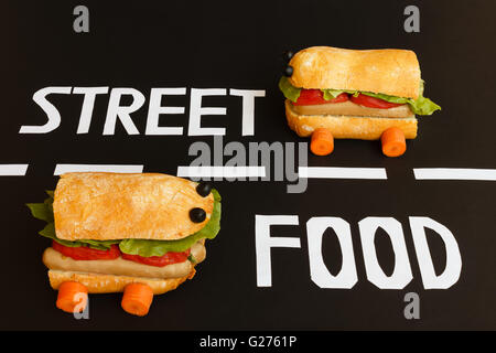 two sandwiches shaped like  a car race in the two lanes of a street where  are placed  the letters  of white colour  that form t Stock Photo