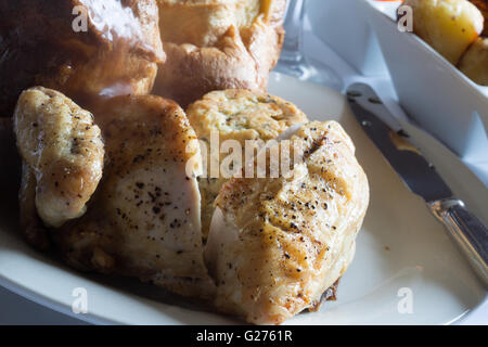 A classic English Sunday roast dinner of Chicken, Sage and Onion stuffing, Yorkshire pudding and gravy, vegetables and potatoes. Stock Photo