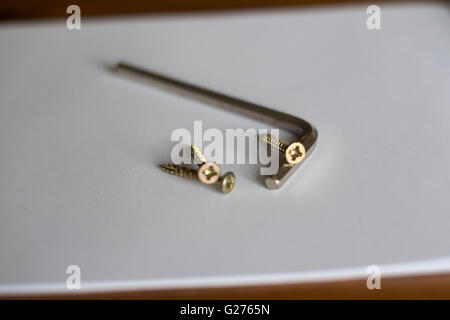 Some Pozidriv / phillips screws on a white background. An Allen / hex socket wrench. Wrong tool. Stock Photo