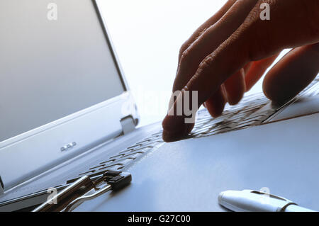 person typing on a laptop backlit Stock Photo