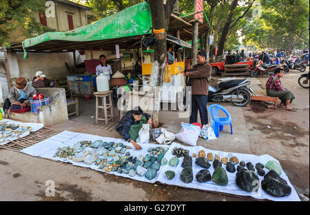 Seller arranges display of pieces of cut and polished jade on sale at the roadside at the Jade Market, Mandalay, Myanmar (Burma) Stock Photo