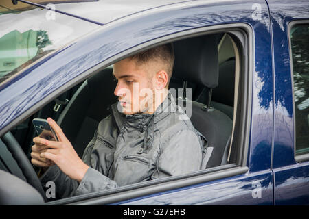 Handsome Young Man using mobile phone while driving a car Stock Photo