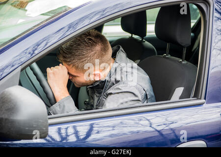 Handsome Young Man sleeping in a Car, resting head on wheel Stock Photo