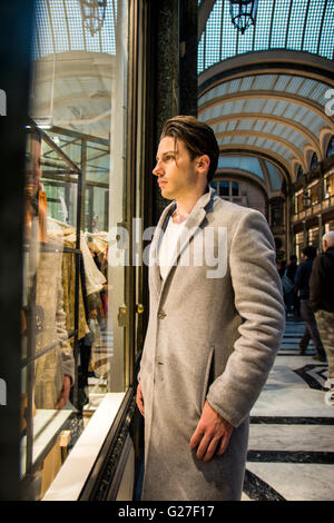 Handsome Young Man in Black Elegant Suit Looking at Displayed Fashion Items in Glass Window Boutique at the High Street Side. Stock Photo