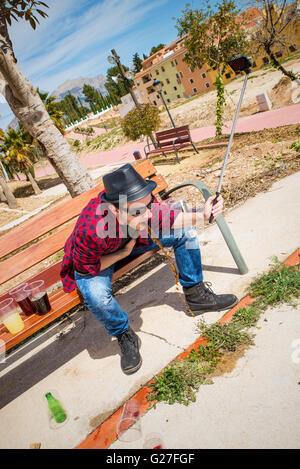 Guy throwing up  on a park bench while taking a selfie Stock Photo