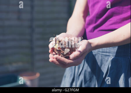 A young woman is doing gardening and i holding some weeds in her hands Stock Photo