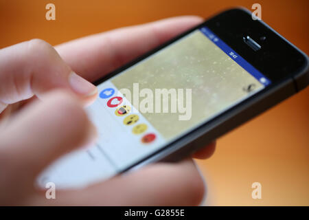 A teenager using reactions on the facebook app on a smart phone Stock Photo