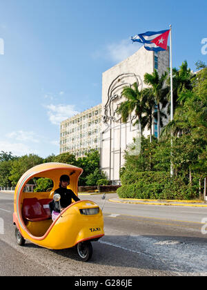 A coco taxi driving past the Ministry of Interior building on Revolution Square with the image of Che Guevara in the background. Stock Photo