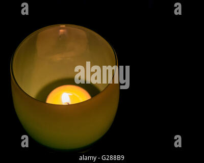 lit tealight in yellow/green round glass holder Stock Photo