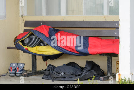 Homeless man sleeping on a bench in Worthing, West Sussex, England, UK. Stock Photo