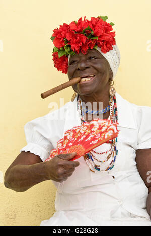 A common sight in the old city of Havana in Cuba - normally an elderly lady will dress in traditional clothes 'smoking' a cigar Stock Photo