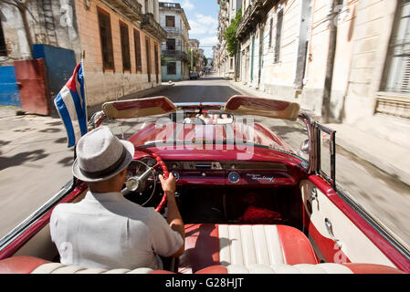 A Cuban taxi driver driving his1955 Pontiac Star Chief convertible in the Old Town of Havana, Cuba. Stock Photo