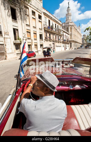 A Cuban taxi driver driving his1955 Pontiac Star Chief convertible in the Old Town of Havana, Cuba. Stock Photo