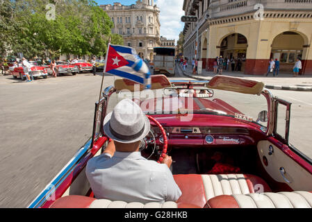 A Cuban taxi driver driving his1955 Pontiac Star Chief convertible in the Old Town of Havana, Cuba. Stock Photo