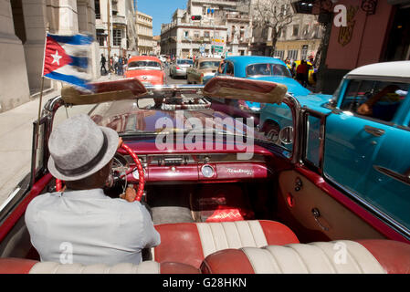 A Cuban taxi driver driving his1955 Pontiac Star Chief convertible in the Old Town of Havana, Cuba. Stock Photo