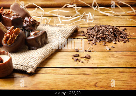 Group of bonbons stacked. Black and white chocolate with nuts and straw decoration on a wood table. Front view. Stock Photo