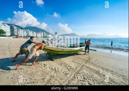 RIO DE JANEIRO - APRIL 4, 2016: Brazilian fishermen launch a fishing boat on a tranquil morning on Copacabana Beach. Stock Photo