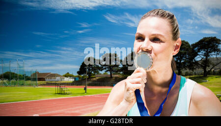 Composite image of portrait of sportswoman kissing a medal Stock Photo