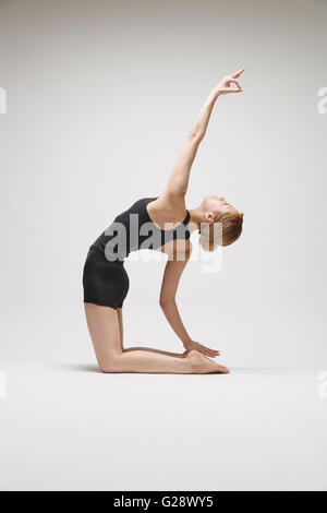 Attractive young Japanese woman wearing black pants and tank top practicing yoga on white background Stock Photo