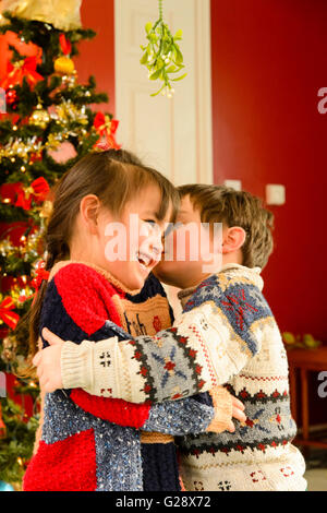 Kids kissing in the house at Christmas Stock Photo