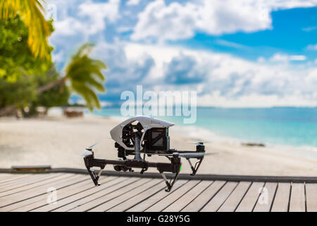 Flying drone with mounted camera at the beach. Palm trees and blue lagoon Stock Photo