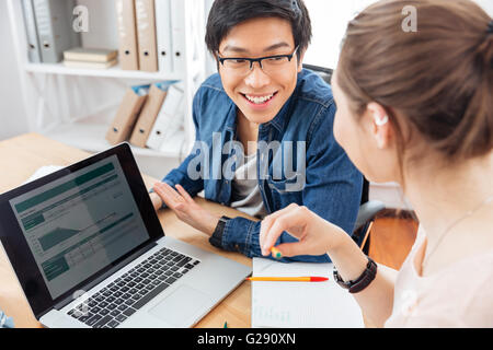 Two happy young businesspeople using laptop and working together Stock Photo