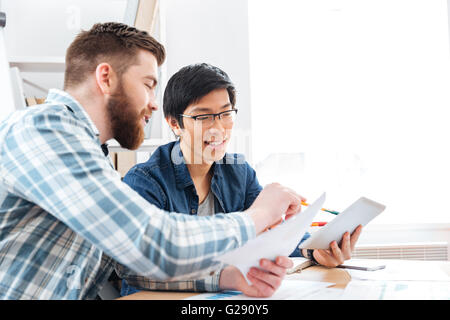 Two young businessmen making business plan and using tablet together Stock Photo