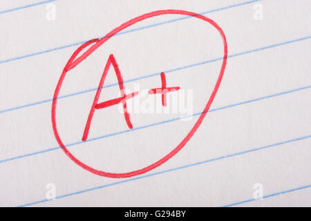 A plus (A+) grade written in red pen on notebook paper. Stock Photo