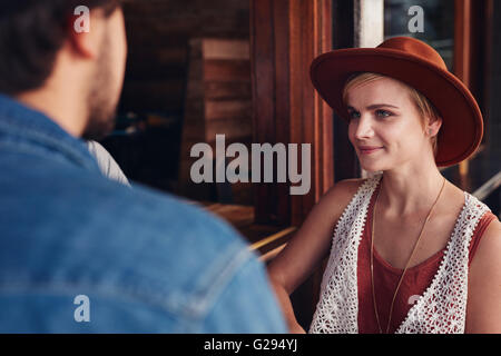 Portrait of beautiful young woman sitting at a cafe with her friend. Stock Photo
