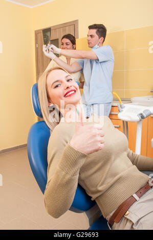 Beautiful and satisfied female patient in dental office showing ok gesture Stock Photo