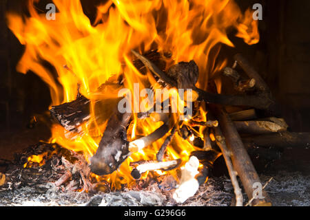 Close-up red and yellow flames in the fire of logs on the brick wall background Stock Photo