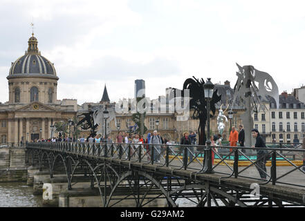 Paris, France. 25th May, 2016. People walks past the statues during an exhibition of the iron works by French artist Daniel Hourde on Pont Des Arts Bridge in Paris, France, May 25, 2016. The exhibition is held from May 25 to June 27. Hundreds of thousands of 'love locks' were once hung on Pont Des Arts Bridge, a foot bridge over the Seine River. © Li Genxing/Xinhua/Alamy Live News Stock Photo