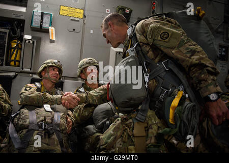 Fort Bragg, NC, USA. 26th May, 2016. Maj. Gen. Richard Clarke, right, shakes hands with Command Sgt. Maj. Benjamin Jones as Lt. Gen. Stephen Townsend looks on while they are in flight on a C-17 cargo plane for the Airborne Review jump on Thursday, May 26, 2016, on Fort Bragg, N.C. The annual Airborne Review included roughly 1,300 paratroopers descending from 20 aircraft, heavy drops, an assault and demolition of a mock enemy compound and displays of artillery and helicopter might. The event was one of the highlights of this year's All American Week, an annual celebration of 82nd Airborne para Stock Photo