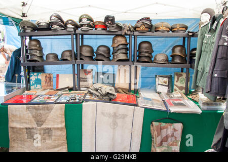 Racks of German world war one and two helmets, stahlhelm, and caps for sale, with uniforms and memorabilia at War and Peace Show in England. Stock Photo