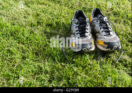 A pair of old running shoes/training shoes on freshly cut grass. Stock Photo