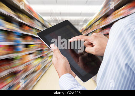 Businessman checking inventory in supermarket on touchscreen tablet. Motion blur Background Stock Photo