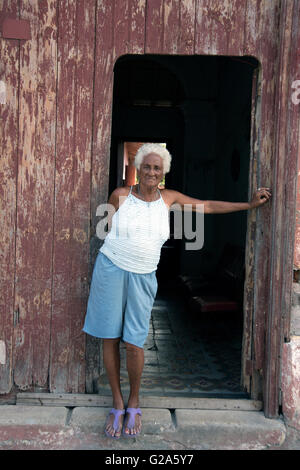 An old Cuban lady stands smiling at the entrance to her home in Cienfuegos Cuba Stock Photo