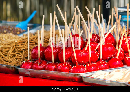 Sweet glazed red toffee candy apples on sticks for sale on farmer market or country fair. Stock Photo