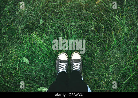 Young man standing in freshly mown grass lawn, top view of casualy dressed youth person in sneakers over mowed grassy field Stock Photo