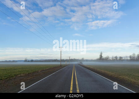 Highway going through plain covered with fog Stock Photo