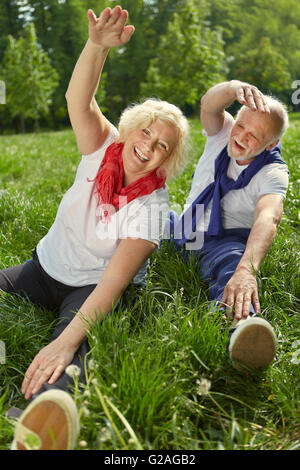 Two happy senior people doing gymnastics and stretching in nature in summer Stock Photo