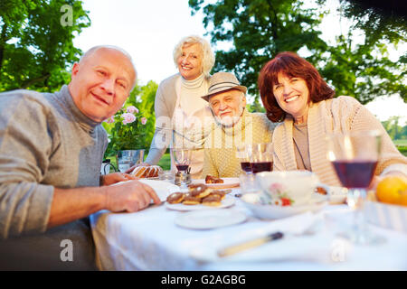Happy senior people sitting at set coffee table in a summer garden Stock Photo
